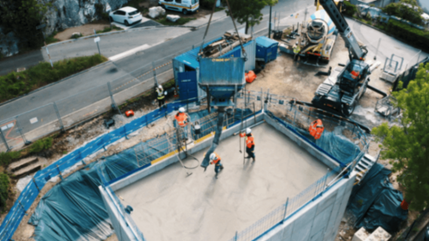 Ouvriers utilisant une pompe a ciments sur chantier a Grenoble.png